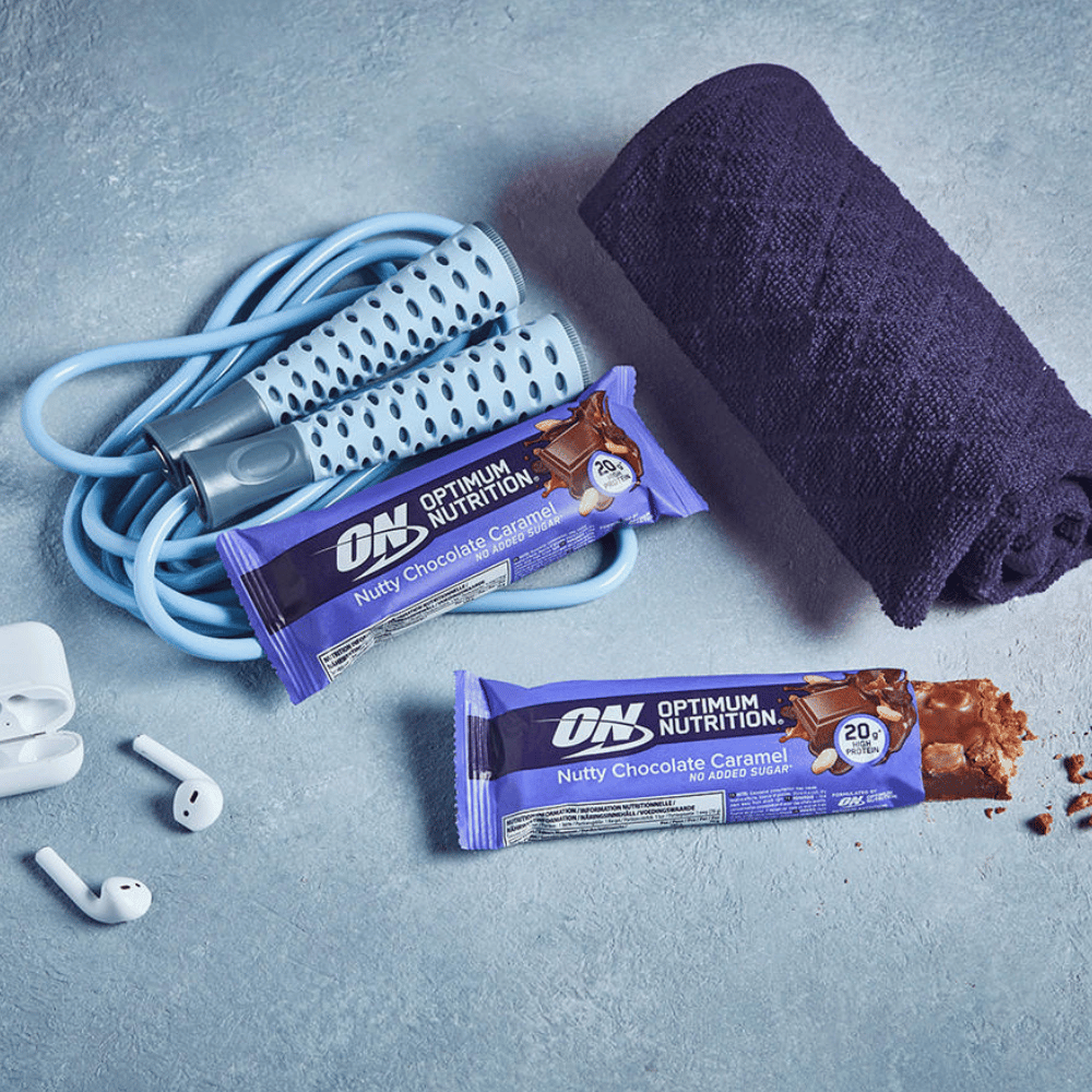 Lifestyle shot of the Optimum Nutrition Nutty Chocolate Caramel Protein Bar with skipping rope and earphones