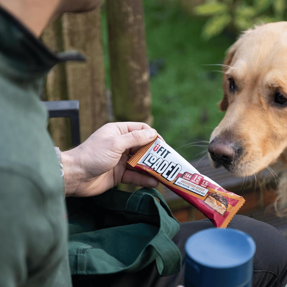 UFIT Caramelised Biscuit Loaded Protein Bar - In hand with dog